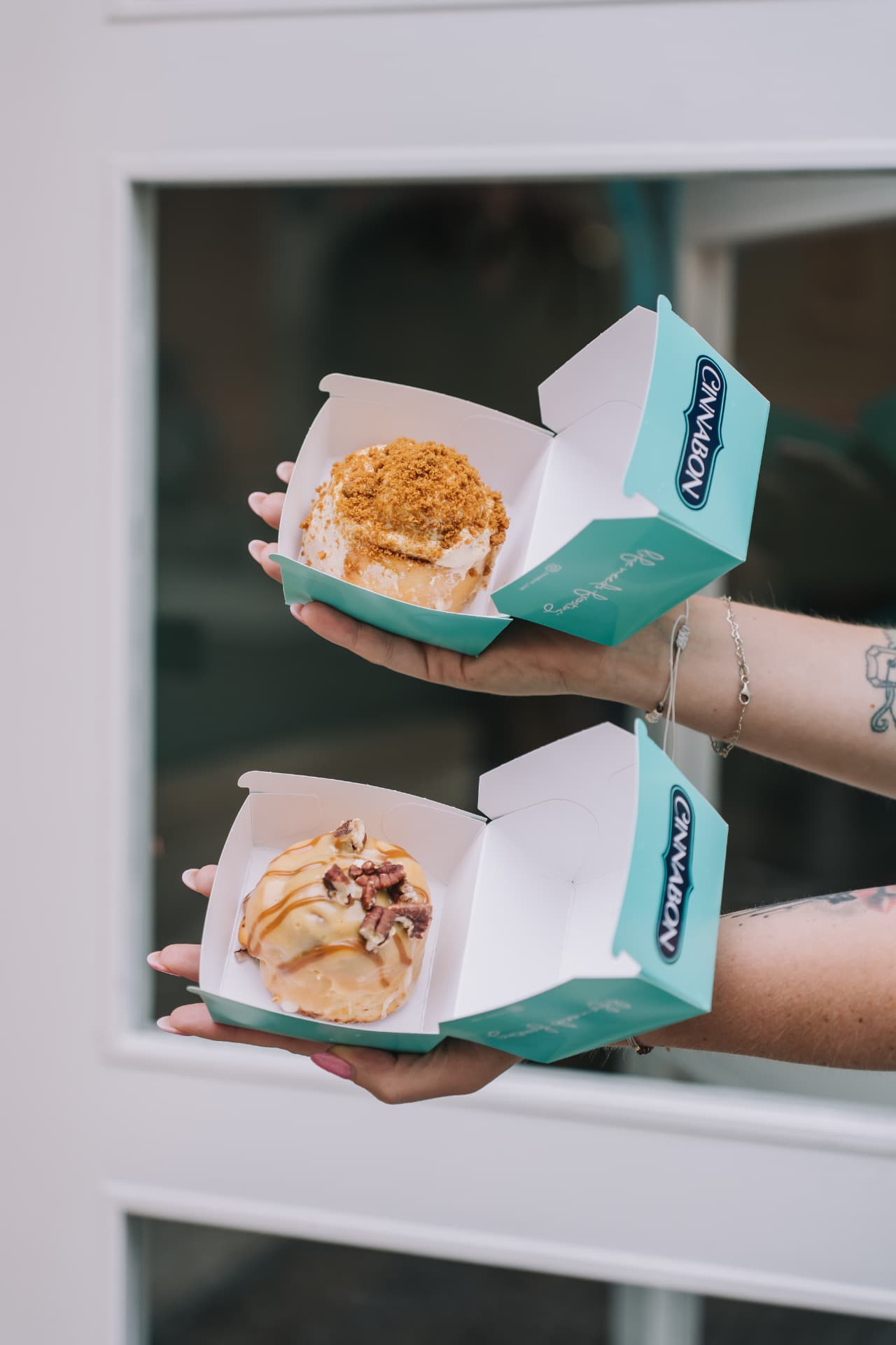 Ruce drží otevřené krabičky s rolkami Cinnabon